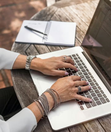 person typing on MacBook Pro on brown wooden table during daytime photo